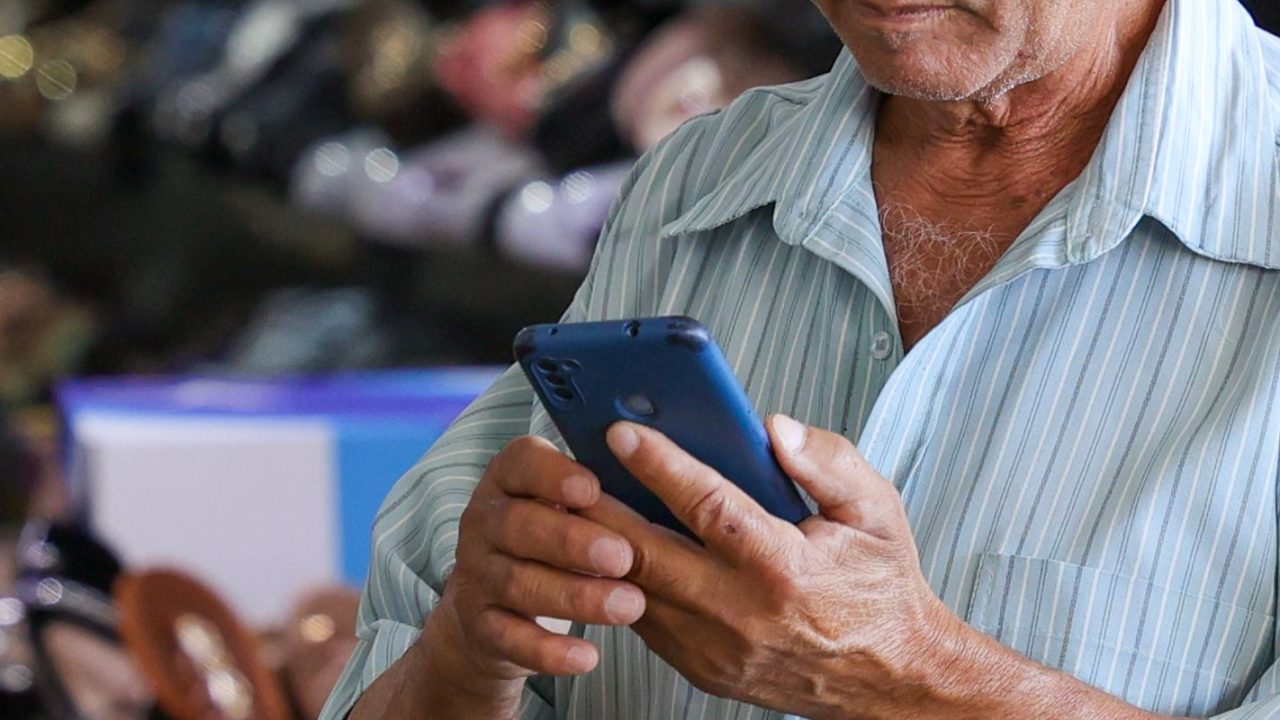 Funcionário da Anatel demonstrando validação biométrica facial para usuários de telefonia móvel