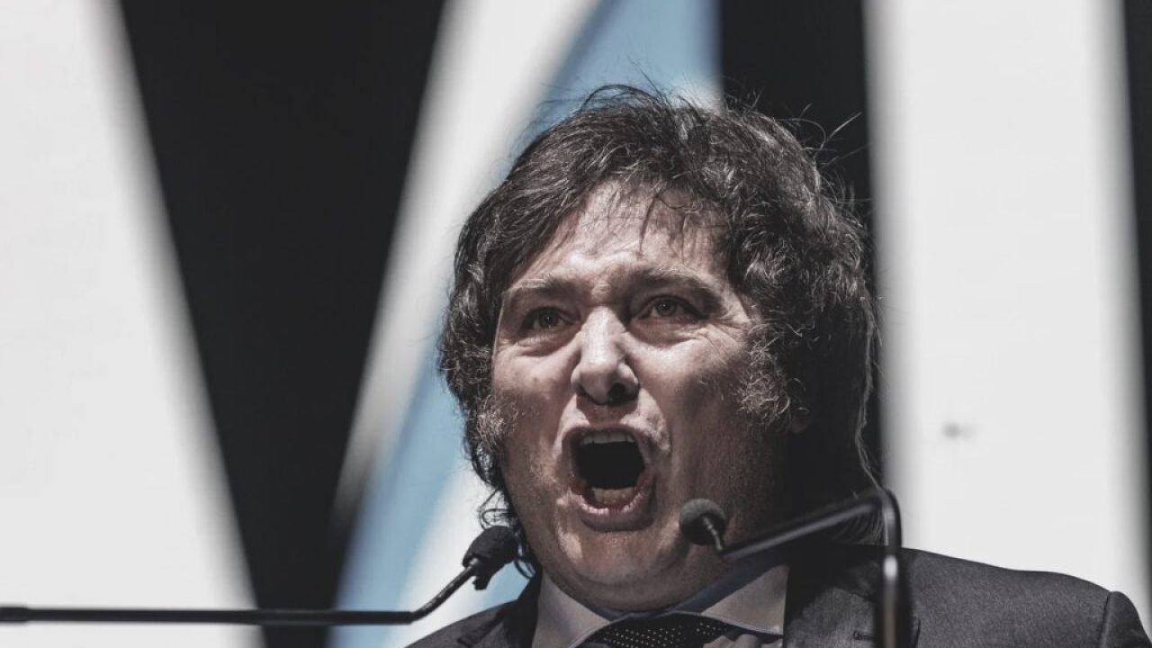 Javier Milei em evento oficial, com gráficos indicando queda de empresas