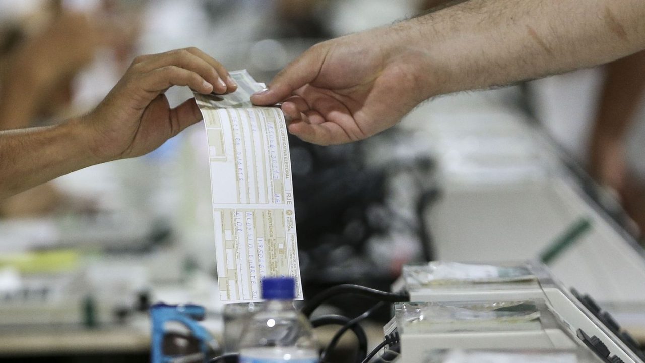 Eleitor preenchendo justificativa de ausência em computador no cartório eleitoral