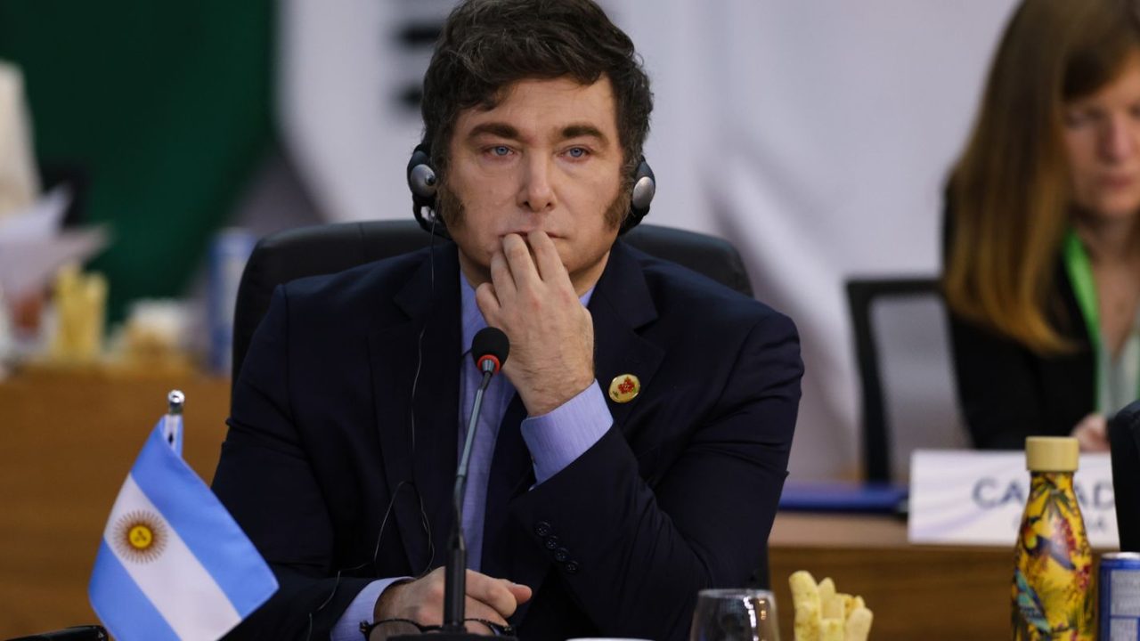 Javier Milei em evento público, ao lado de bandeira da Argentina