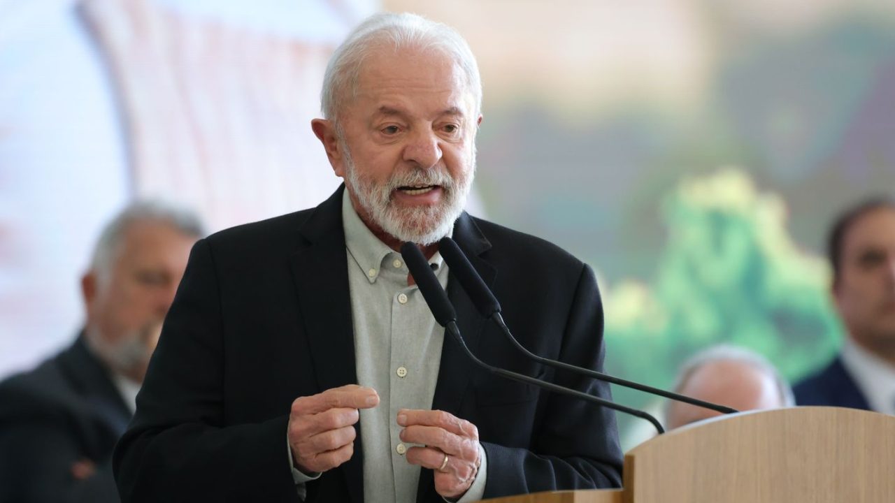 Lula discursando em comício com destaque para documentos de propostas econômicas