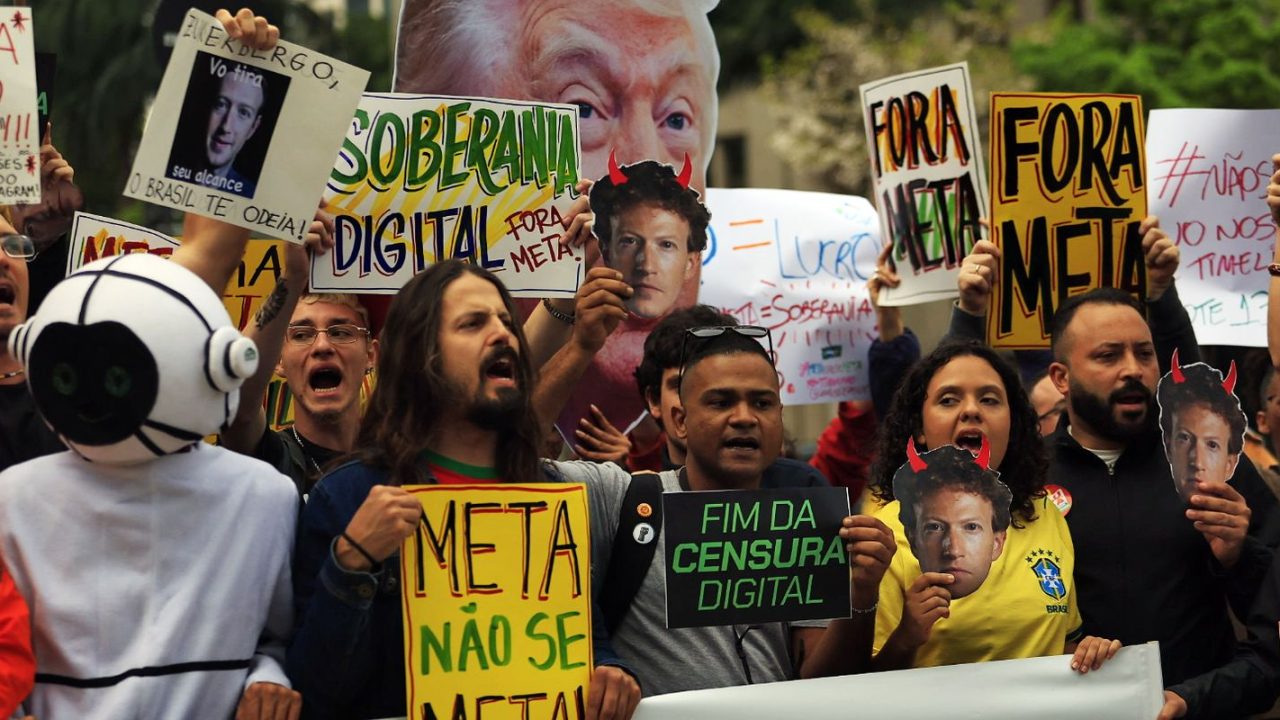 Manifestantes segurando cartazes em frente à sede da Meta em São Paulo