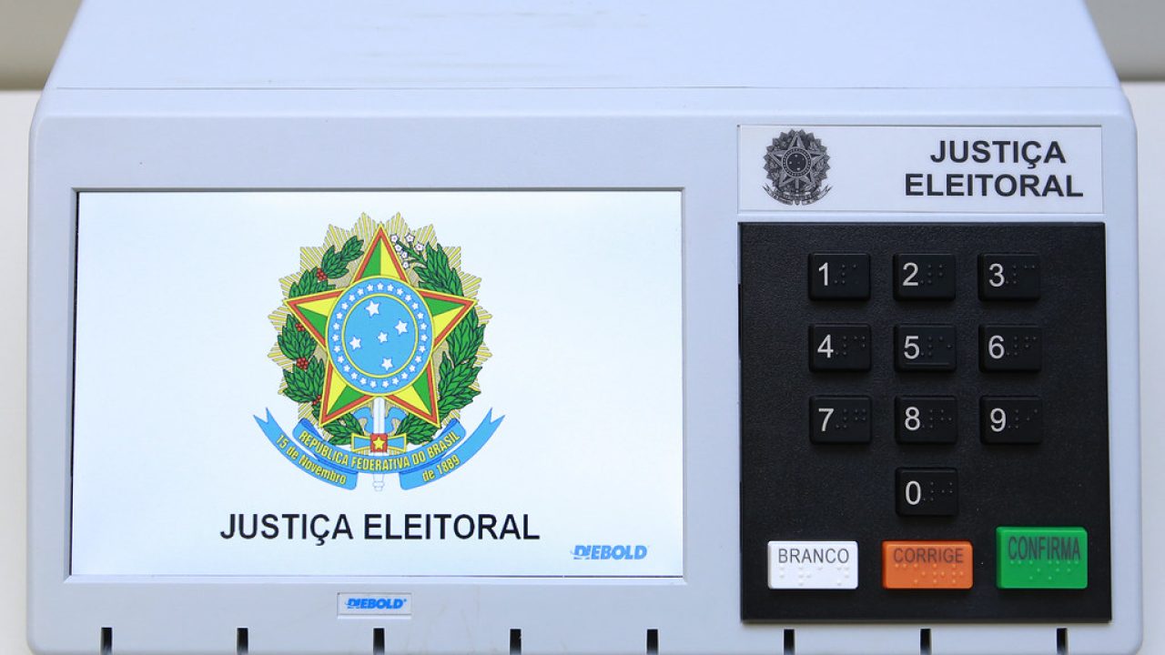 Aluno de 10 anos carregando mochila em formato de urna eletrônica na escola de Uberlândia