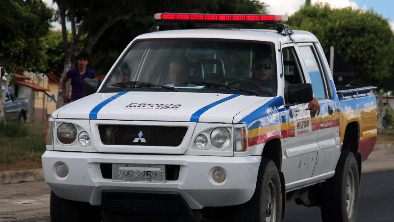Policial militar em uniforme ao lado de motocicleta, em ambiente urbano