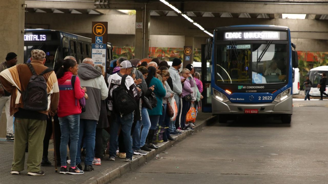 Fila de passageiros aguardando ônibus parado em ponto de São Paulo durante eleição